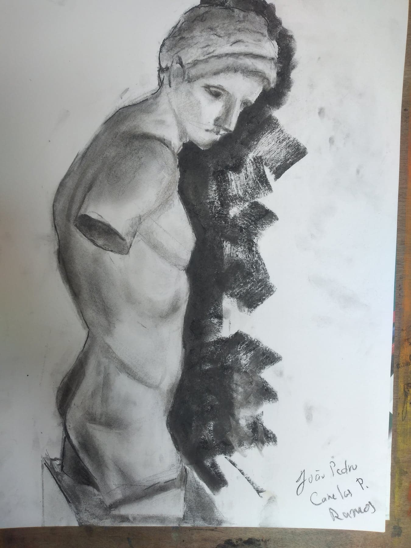 Charcoal reclining figure study photographed on a studio drawing board.