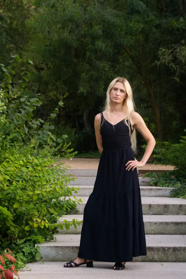 Full-length modeling portrait of Luna in a black dress on garden steps.