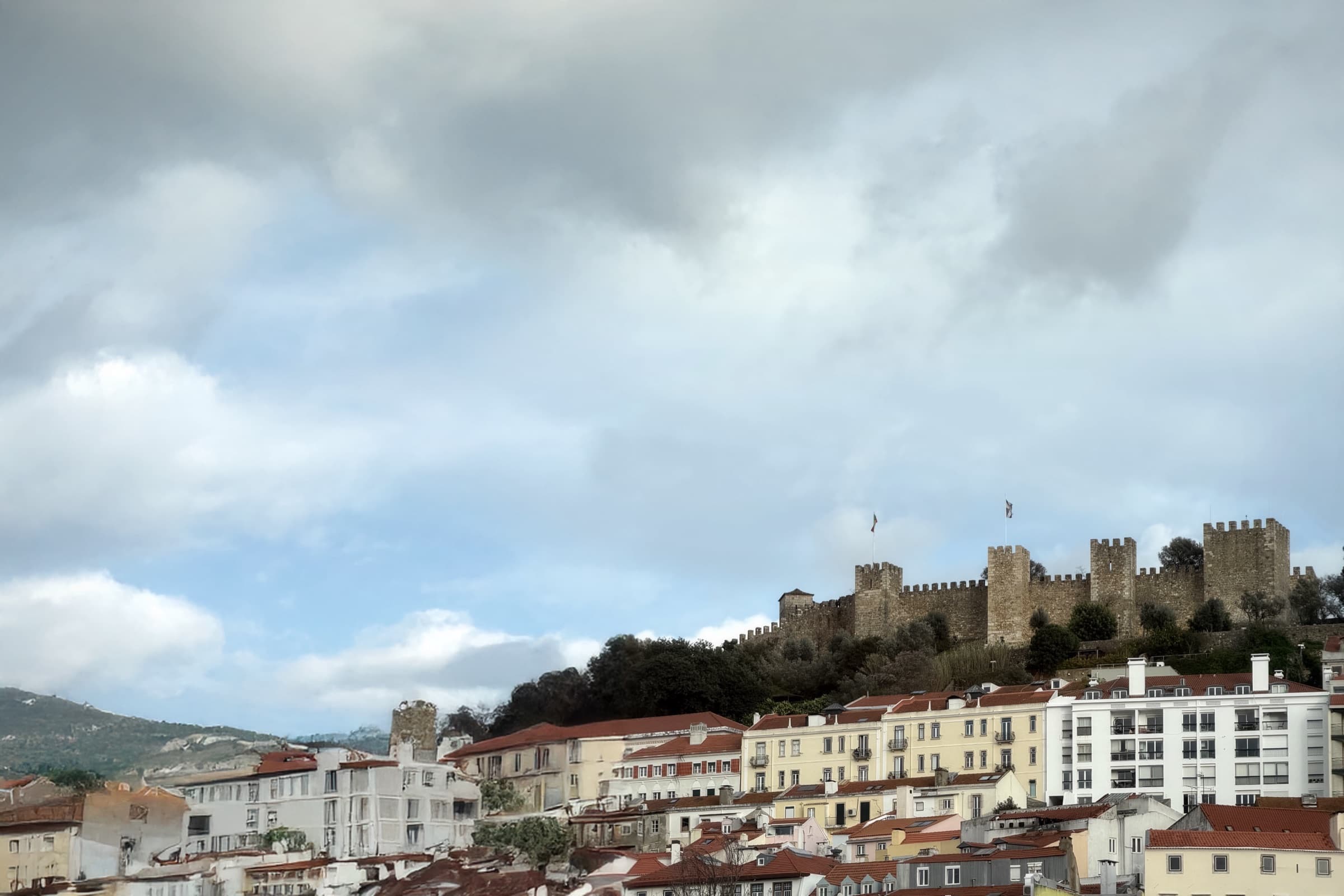 A castle ridge and city buildings sit beneath a dramatic blue-gray sky.