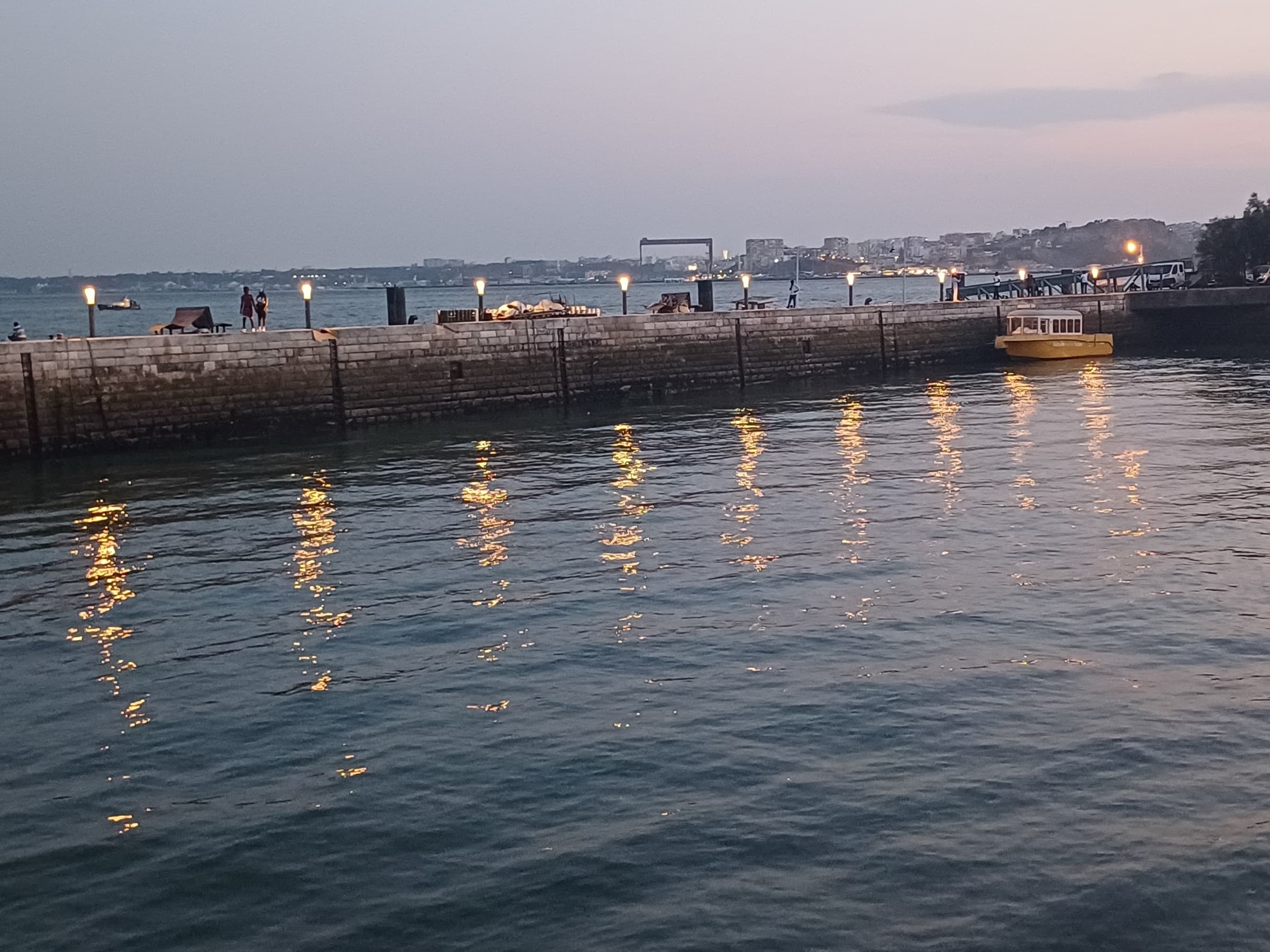 Night water at a Lisbon quay with soft reflections and a distant shoreline.
